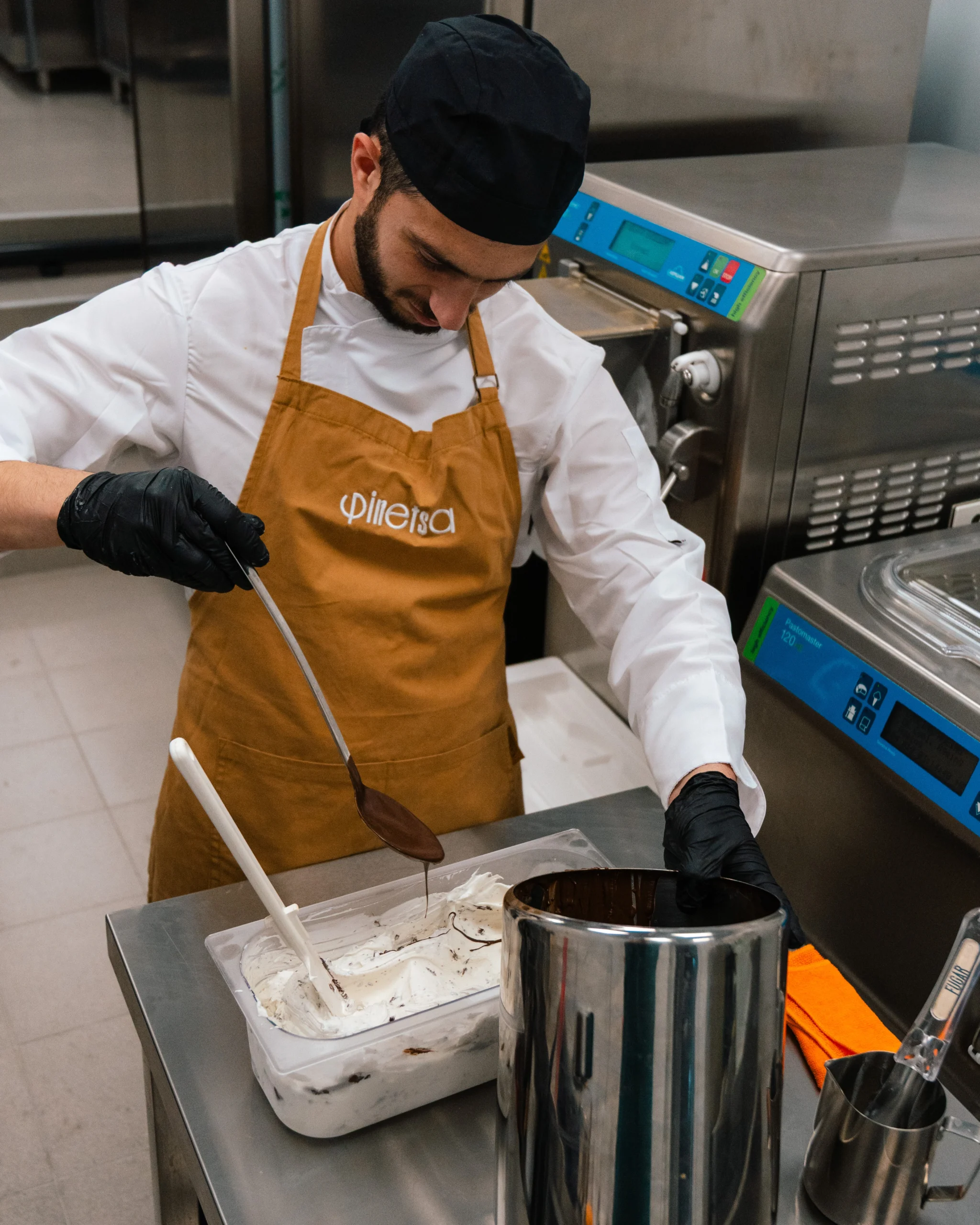 Ο pastry chef της Φinetsa Cremeria προσθέτει ρευστή σοκολάτα σε φρέσκο, χειροποίητο gelato κατά τη διάρκεια της παραγωγής στο εργαστήριο.